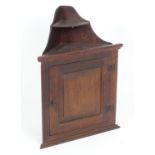 A late 18thC oak corner cupboard with shaped graduated shelves above a single door and wrought