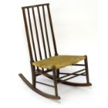 An early 20thC Arts & Crafts style rocking chair with a shaped top rail and spindled backrest