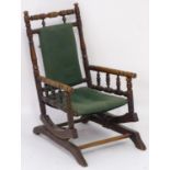 An early 20thC childs rocking chair with a ring turned frame above a cloth seat and turned spindle