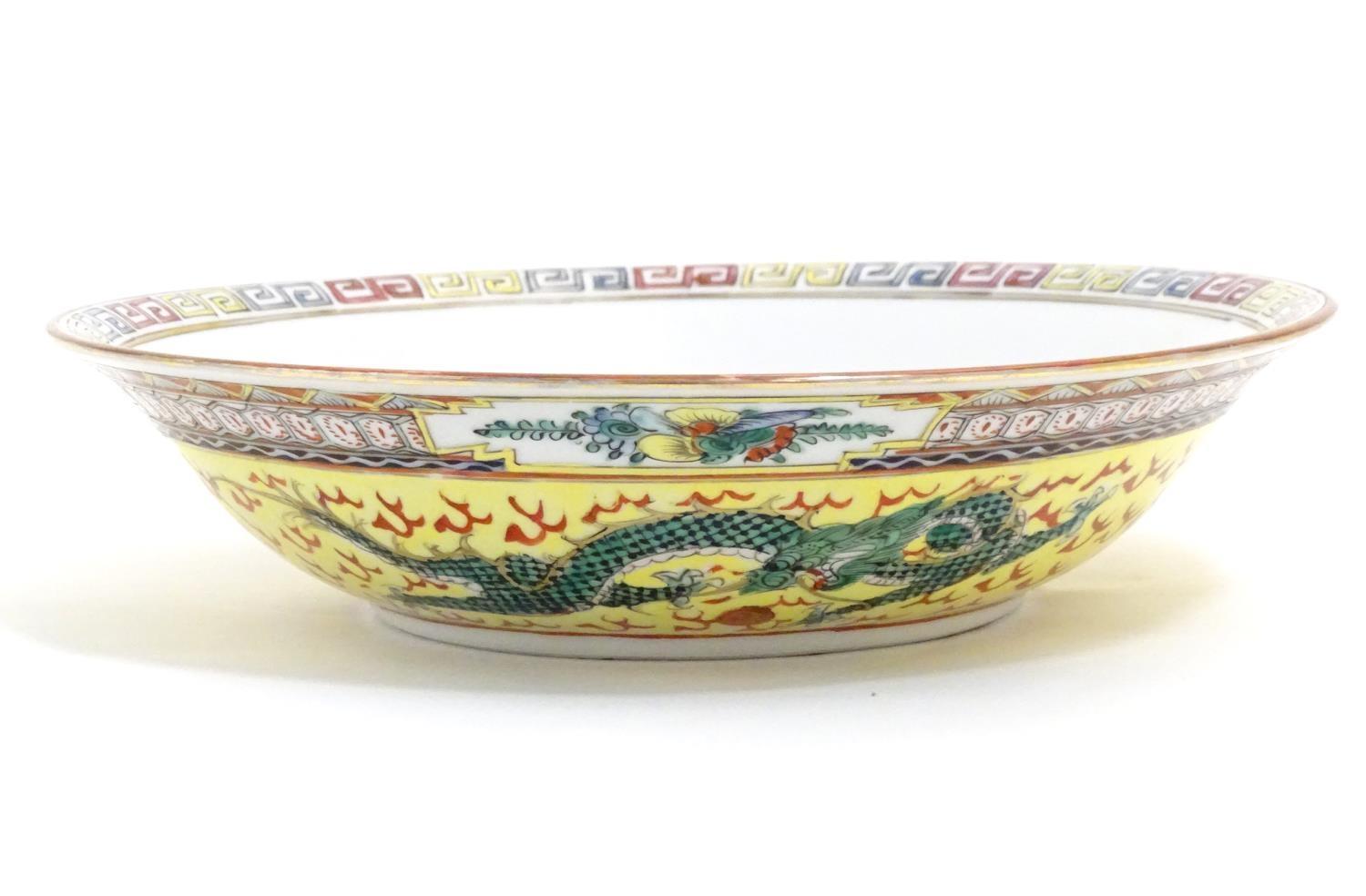 A Chinese famille jeune bowl decorated with two dragons and patterned border. Character marks under.