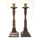 A pair of early 20thC carved wooden candlesticks of squared form with brass sconces. Approx. 14"