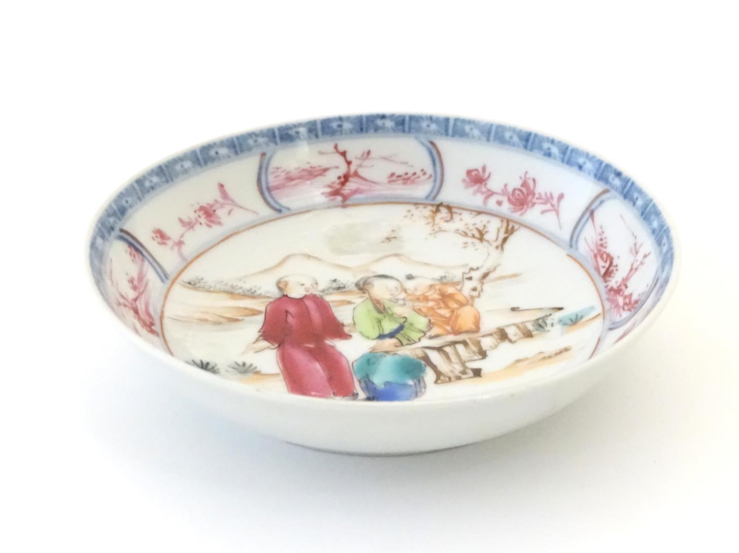 An Oriental famille rose dish depicting a mountainous landscape scene with two figures and a child