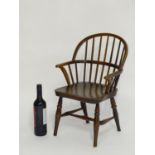 A mid 19thC childs Windsor chair with a double bow back above an elm seat and turned tapering legs