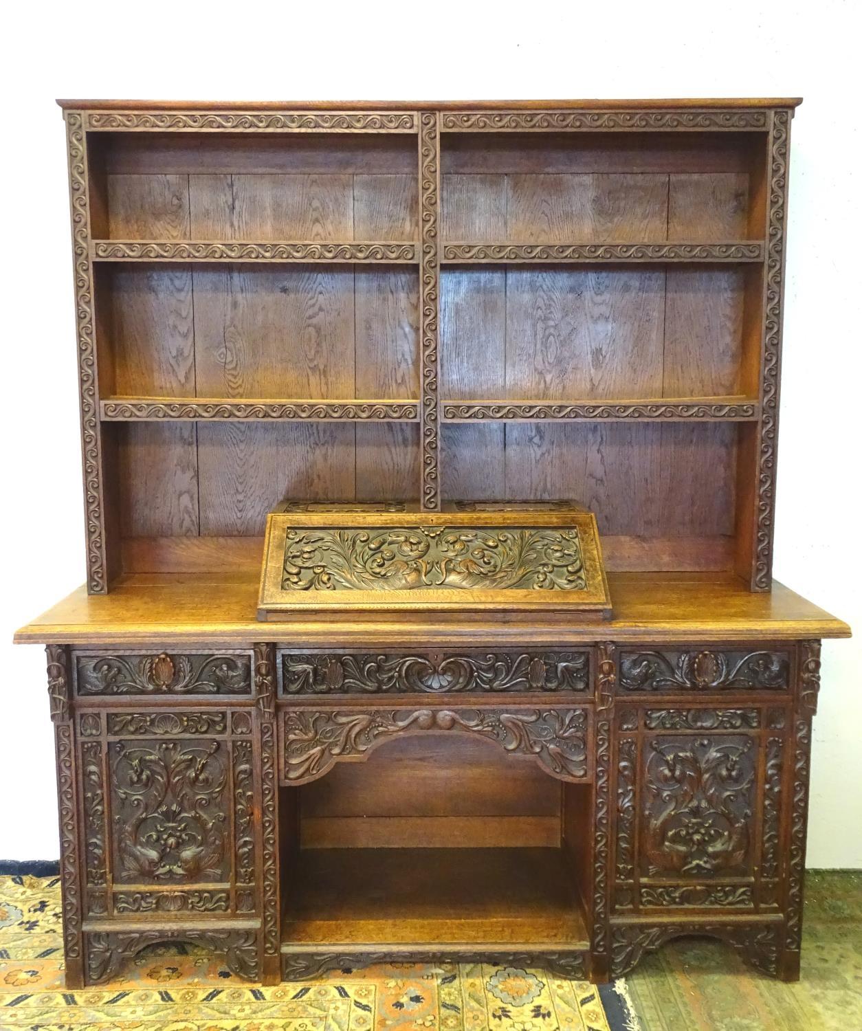 An early 20thC dresser with a blind fretwork carved plate rack above a carved slope and three