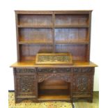 An early 20thC dresser with a blind fretwork carved plate rack above a carved slope and three