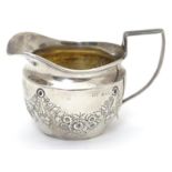 A silver cream jug decorated with floral swags and with part gilded interior. Hallmarked