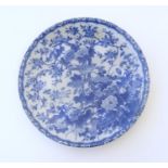 An Oriental blue and white plate with floral and foliate detail with birds on branches. The