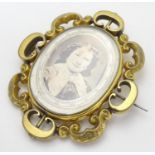 A Victorian gilt metal brooch of locket form with glazed font and back central section within a C-