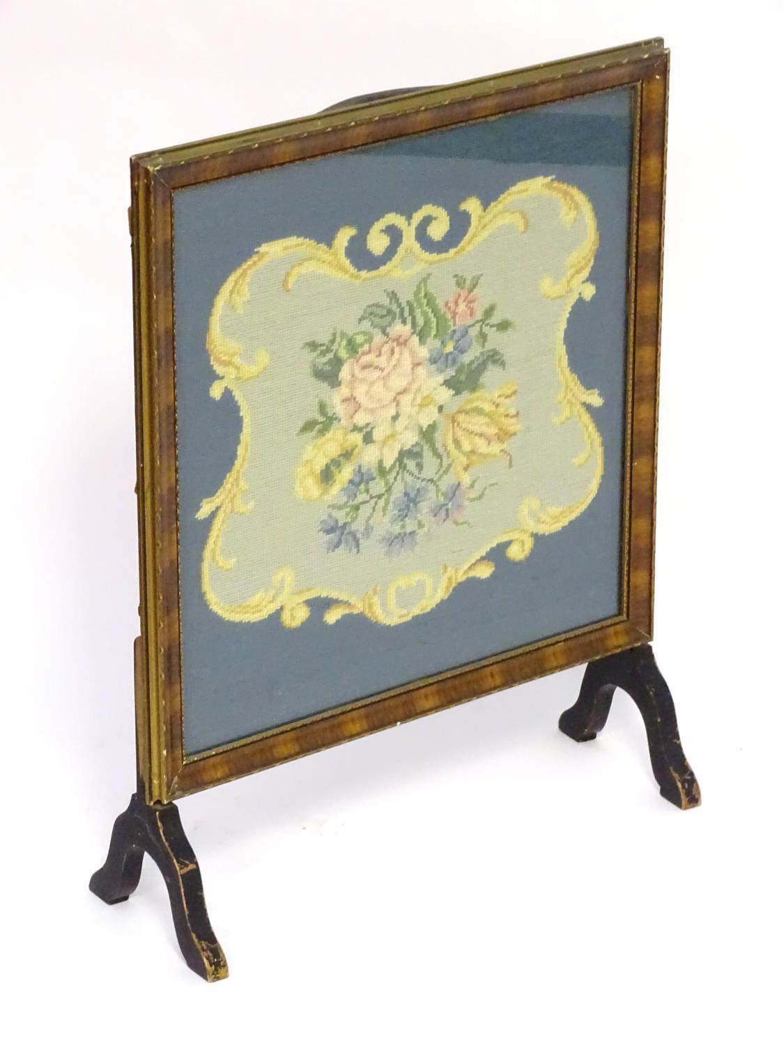 A 20thC fire screen with a moulded surround above a glazed needlework centre. 22" wide x 28" high.