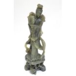An Oriental carved soapstone figure of a lady holding a fan, wearing flowing robes, on a carved