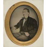 * Ambrotype. A hand-tinted ambrotype of a man seated at a table smoking, probably Spanish, c. 1870s