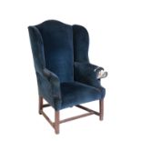 A GEORGE III OAK AND UPHOLSTERED WINGBACK ARMCHAIR