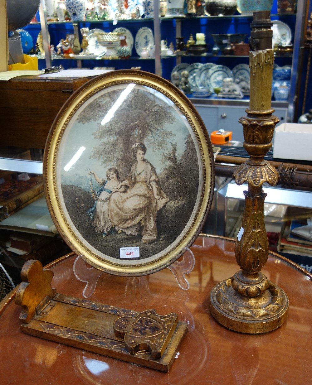 A REGENCY OVAL PRINT in a gilt frame, a giltwood table lamp and a similar book slide (3)