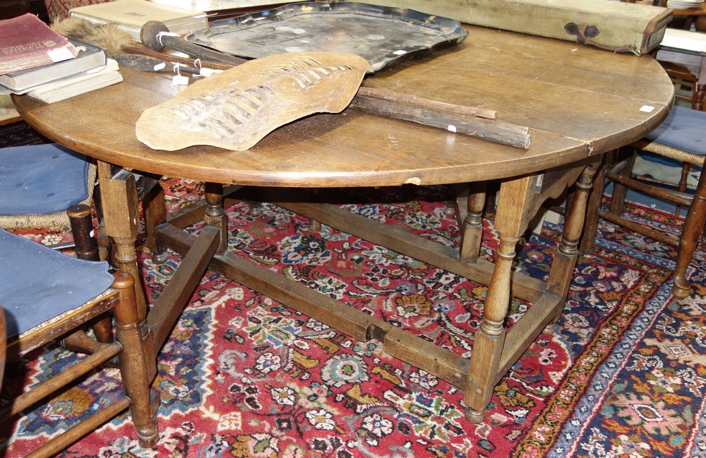 A LARGE OAK GATELEG DINING TABLE the drawers made from old carved coffer panels, 166cm wide (open)