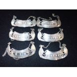 A SET OF SIX WHITE METAL DECANTER LABELS, decorated with 'Ho-Ho' birds(6)