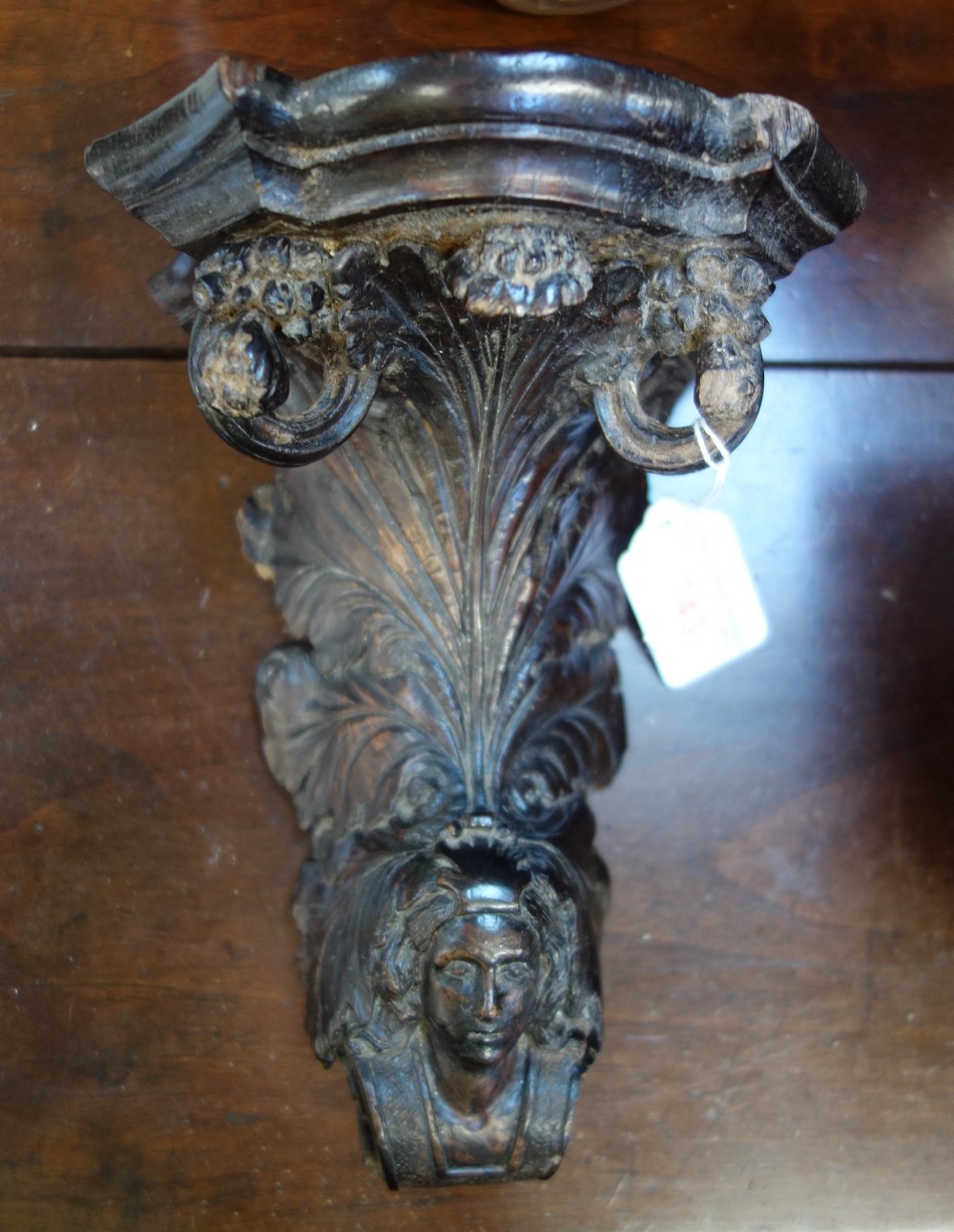 A 19TH CENTURY CONTINENTAL CARVED WALNUT CORBEL with foliage and scrolls emerging from a head