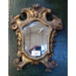 A 19TH CENTURY FLORENTINE GILT WOOD MIRROR of cartouche form, of small proportions, 25cm wide