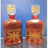 A PAIR OF BOHEMIAN RUBY OVERLAID CUT GLASS DECANTERS with gilt decoration, 25cm high
