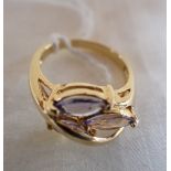A THREE STONE TANZANITE RING, three marquise-cut tanzanite, overlaid with a raised yellow gold loop,