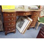 A REPRODUCTION MAHOGANY SERPENTINE FRONTED DESK with green leather top, 116cm wide