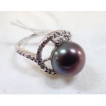 A BLACK SIMULATED PEARL DRESS RING, the pearl with green / mauve hues, on a silver shank, ring