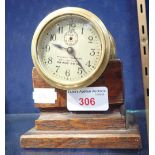 AN EDWARDIAN BRASS CASED, 'KEYLESS' CLOCK, 7cm dia. on an oak stand