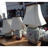 THREE TABLE LAMPS in the form of Chinese vases on wooden stands, each with cream shades