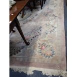 A LARGE CHINESE RUG, with light pink ground, a central floral medallion surrounded with laurel,