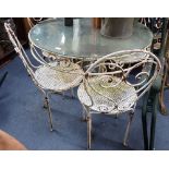 A CONTINENTAL STYLE SCROLLING METAL AND GLASS TOPPED GARDEN TABLE with four chairs, the table 90cm d