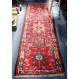 A PERSIAN STYLE WOVEN WOOL RUNNER, WITH FIVE GEOMETRIC MEDALLIONS WITHIN A BORDER, IN GREENS, BLUES,