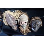 A CARVED WOODEN TRIBAL MASK with cowrie shells and two others similar (3)