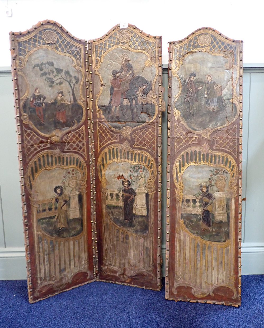 A ROCOCO STYLE 'SPANISH' LEATHER FOLDING SCREEN of small proportions decorated with vignettes of peo