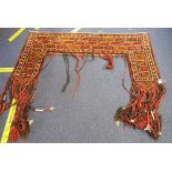 AN AFGHAN TURKOMAN KAPANUK, or door hanging 145cm wide, the sides dropping to 77cm, plus long fringe