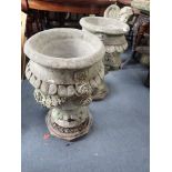 A PAIR OF RECONSTITUTED GARDEN URNS decorated with roses, 65cms high