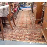 A LARGE RED GROUND PERSIAN RUG, OF GEOMETRIC DESIGN (faded, worn and insect damaged) 350cm x 445cm