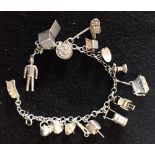 AN UNMARKED WHITE METAL CHARM BRACELET, with attached silver and unmarked white metal charms