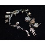 AN UNMARKED WHITE METAL CHARM BRACELET