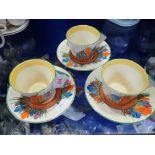 CLARICE CLIFF; THREE CROCUS CUPS AND SAUCERS with Art Deco handles (one cup broken)