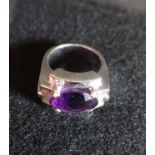 AN "AMETHYST" DRESS RING, on an unmarked white metal shank, with ribbed shoulders, ring size M