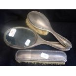 A SILVER BACKED DRESSING TABLE SET, comprising, two brushes and a mirror