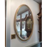 AN EDWARDIAN OVAL GILT FRAMED MIRROR WITH BEVELLED PLATE