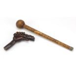 Two carved wood walking stick handles including one carved with a hand clenching a scroll, the