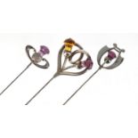 Three Art Nouveau unmarked silver thistle design hat pins set with amethyst and citrine, the largest