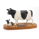 Beswick connoisseur model of a Friesian cow and calf, raised on a wooden plinth base, 34cm wide :For