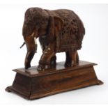 Large Indian carved rosewood elephant with ivory inlay, raised on a tapering block base, 36.5cm high
