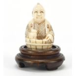 Japanese carved ivory Netsuke of a man in a barrel, raised on a hardwood stand, character marks to