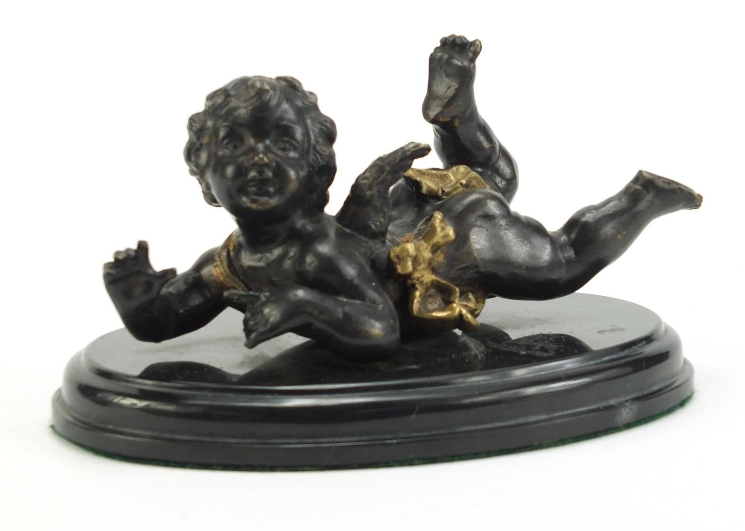 Classical patinated bronze figure of Putti raised on an oval marble base, 18.5cm wide :For Further