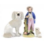 Two Staffordshire dogs and a figure of a boy holding a bird, the largest 29cm high :For Further