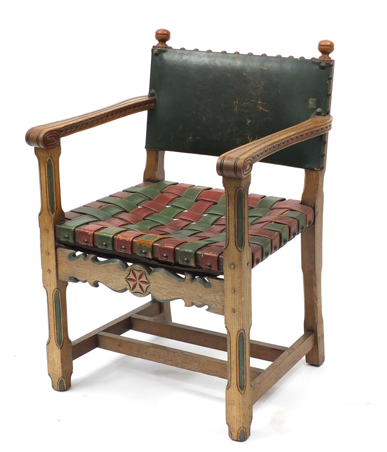 Carved oak open arm chair with red and green leather strap seat, 85cm high :For Further Condition