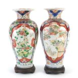 Pair of Japanese Imari porcelain vases raised on carved hardwood stands, hand painted with
